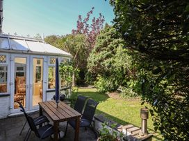 A garden with a table and chairs near a conservatory at Honey Cottage Ilfracombe