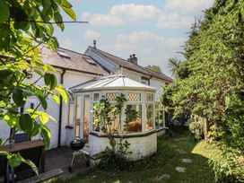 A conservatory with plants in the garden at Honey Cottage in Ilfracombe