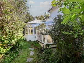 A garden with a conservatory and pathway at Honey Cottage in Ilfracombe