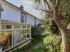 A garden with a conservatory and bird feeder at Honey Cottage in Ilfracombe