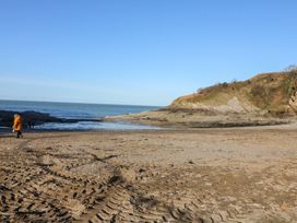 A beach with a person walking near the shore at Honey Cottage in Ilfracombe