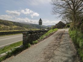 A road with a stone wall and a house at Ysgoldy in Dolwyddelan