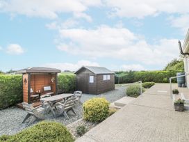 A garden with a table and chairs near two outdoor sheds at Dunbrody Dreams