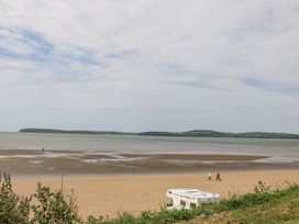 A beach with people walking and a caravan at Dunbrody Dreams