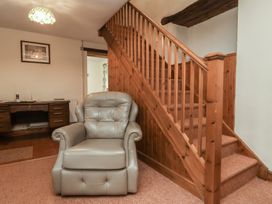 A living room with a chair and staircase at Denhill Cottage