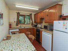 A kitchen with wooden cabinets and appliances at Denhill Cottage