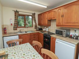 A kitchen with wooden cabinets and appliances at Denhill Cottage