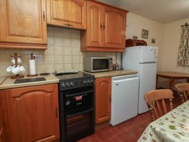 A kitchen with wooden cabinets and appliances at Denhill Cottage 