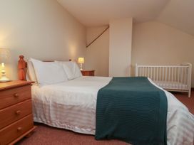 A bedroom with a bed and crib at Denhill Cottage