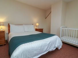 A bedroom with a bed and cot at Denhill Cottage