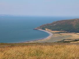 A coastline with a beach and hills overlooking the sea at Denhill Cottage