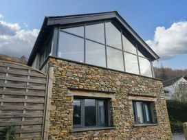 An exterior view of a house with stone walls and large windows at Two Hollens in Ambleside