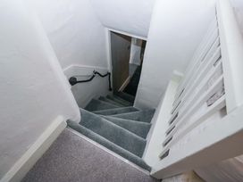A staircase with a handrail and door at Two Hollens in Ambleside
