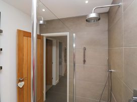 A bathroom with a shower and wooden door at Two Hollens in Ambleside