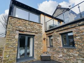 An exterior view of a property with stone walls and glass features at Two Hollens in Ambleside