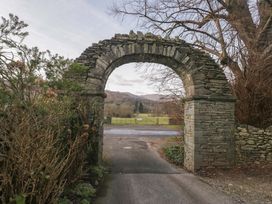 A stone archway with shrubbery and a field beyond at Two Hollens in Ambleside