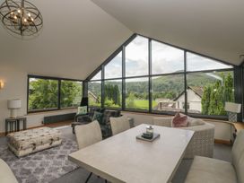A living room with large windows and a table at Two Hollens in Grasmere