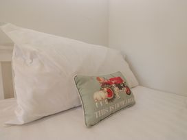 A bed with a white pillow and a decorative pillow at Two Hollens in Grasmere