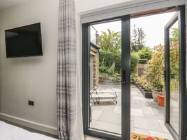 A bedroom with a television and sliding doors leading to a patio at Two Hollens in Grasmere