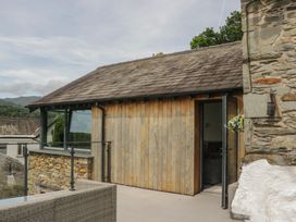 An outdoor area with a stone wall and wooden structure at Two Hollens in Grasmere