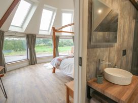 A bedroom with a bed and a bathroom sink at Yr Awen in Lampeter
