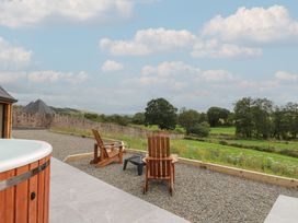 An outdoor area with a hot tub and wooden chairs at Yr Awen in Lampeter