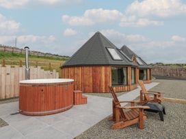 An outdoor area with a hot tub and wooden chairs at Yr Awen in Lampeter