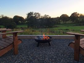 An outdoor area with a fire pit and wooden chairs at Yr Awen Near Lampeter