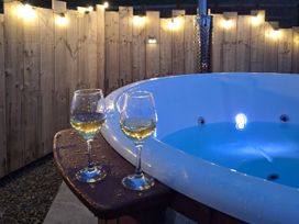 A hot tub with two glasses on a wooden table near lights at Yr Awen - Inspiration near Lampeter