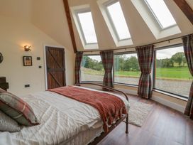 A bedroom with a bed and large windows at Y Cwlwm in Lampeter