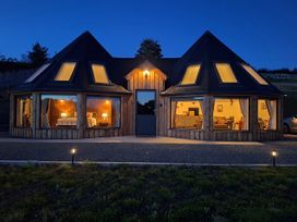 A house with illuminated windows and a door at Y Cwlwm - The Celtic Knot Near Lampeter