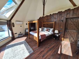 A bedroom with a wooden bed and window at Y Cwlwm - The Celtic Knot Near Lampeter
