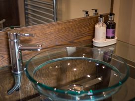 A bathroom with a glass sink and soap dispensers at Souterstead in Torver near Coniston