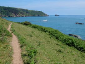 A coastal path with a boat on the water at Home by the Harbour, Dartmouth