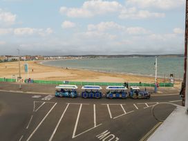 A beach with sand and a train on the road at 9 The Esplanade