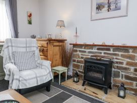 A living room with a fireplace and an armchair at Ocean Cottage in Bude