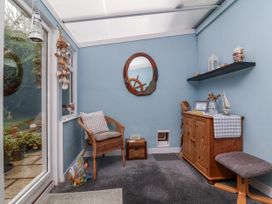 A conservatory with a chair and a storage unit at Ocean Cottage Bude