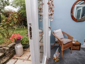 A conservatory with a chair and plants at Ocean Cottage in Bude