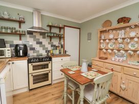 A kitchen with a stove and table at Ocean Cottage in Bude