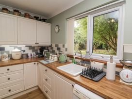 A kitchen with a sink and window overlooking a garden at Ocean Cottage in Bude