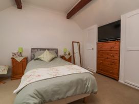 A bedroom with a bed, side tables, and a dresser at Ocean Cottage, Bude