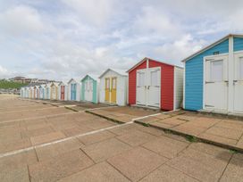Beach huts lined up on a pavement at Ocean Cottage in Bude