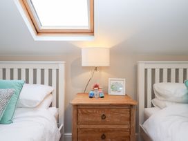 A bedroom with two beds and a bedside table at 3 Keepers Cottage