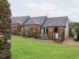 An outdoor view of a cottage with decking and grass at 3 Keepers Cottage 