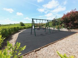 A playground with swings and rubber surface at 3 Keepers Cottage in 