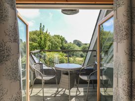 A balcony with a table and chairs overlooking greenery at 3 Keepers Cottage, Hillfield Village