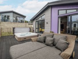An outdoor area with a hot tub and sofa at Minack Lodge in Redruth