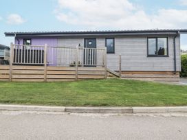 A house with a fence and grass in front at Minack Lodge in Redruth