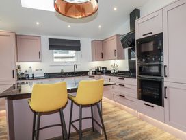 A kitchen with bar stools and cooking appliances at Minack Lodge in Redruth