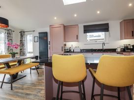 A kitchen with bar stools and a dining table at Minack Lodge in Redruth